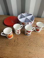 Four mugs and open divided storage box on table