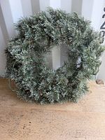 Front view of artificial pine wreath showing shape, branch density and attached light string
