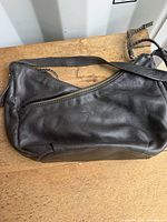 Front view of brown leather purse showing zipper pocket and strap