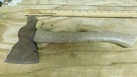 Full view of combination axe showing steel head, nail slot, wood handle, ruler for scale