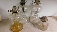 Front view of four glass oil lamps showing sizes and colors