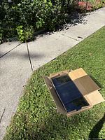 Cardboard box containing clear glass panels on grass