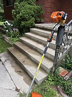 Full view of trimmer leaning against porch steps