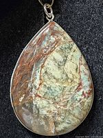Front view of teardrop scenic jasper pendant in silver bezel