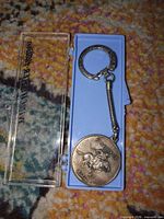 Keychain in open blue plastic case, full view