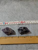 Two rough amethyst stones beside rulers showing approx 2-2.5 in. length