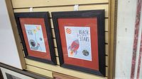 Both framed prints side by side on slat wall