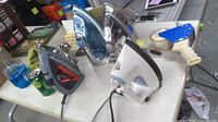 Four corded steam irons on table