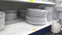 Stacks of round white plates on bottom shelf
