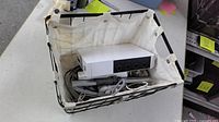 Wii console with exposed GameCube ports and bundled cables inside basket