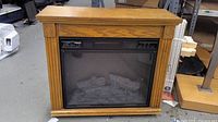Front view of oak electric fireplace heater showing cabinet design and glass insert