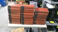 25 red hardcover books stacked on table