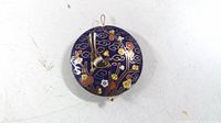 Front view of circular cloisonné pendant showing crane and floral design