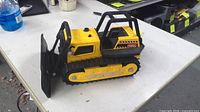 Left side view of yellow Tonka bulldozer with black blade