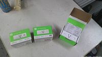 Three WeMo Smart Plug boxes on table, two closed, one opened showing plug