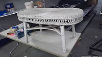 Side view of complete white wicker coffee table on work surface