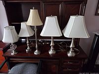 Five nickel finish table lamps on desk