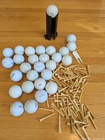 Group of golf balls, wood tees, black dispenser and white divot tool