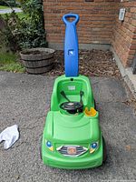 Front view showing green body, blue push handle, steering wheel and cup holder