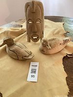 Mask and both duck carvings displayed together on leather