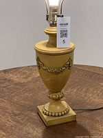 Full view of mustard yellow urn-style lamp on table