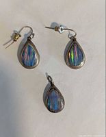 Front view showing two earrings and pendant with opal inlay