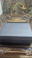 closed textured black jewelry box on ornate frame