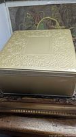 closed embossed gold-tone tin resting on wooden surface