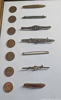 All seven brooches with coins for scale