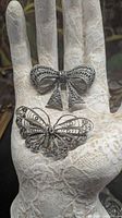 Butterfly and bow brooches on display hand, showing size and detail
