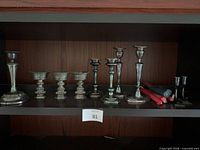 Full shelf view showing all candlesticks and ornate cups