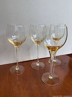 Four yellow-tinted Mosel wine glasses on wood surface