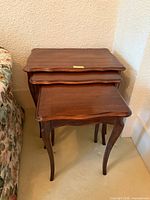 Three mahogany nesting tables stacked together showing tops and legs