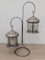 Full view of metal stand with two hanging lanterns and candles