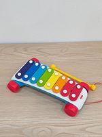 Full view of xylophone showing rainbow bars, wheels, mallet