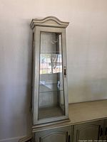 Full view of curio cabinet front showing finish, door and shelves