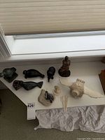 Full group of soapstone carvings, bone bird, inkwell and picks displayed on window ledge