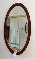 Full view of oval mahogany wall mirror on wall