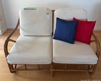 Front view of rattan loveseat with cushions and pillows
