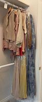 Closet rod view showing layered blouses and dresses, some in garment bags