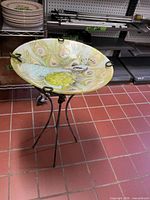 Full view of glass bird bath on metal stand