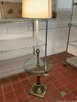Full view of brass floor lamp with shade and glass table