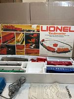 Overall view of box, styrofoam tray with rolling stock, track, transformer and manual