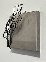 side view of square metal plaque with projecting wire branches