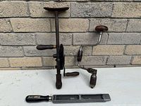 Overall shot of three woodworking tools: breast drill standing, brace drill lying, rasp in foreground
