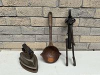 Group shot of flat iron, ladle, and mechanical tool
