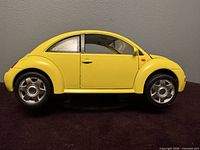 Left side profile of yellow Volkswagen New Beetle model