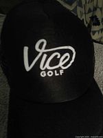 Front view of black Vice Golf trucker hat showing white logo and curved brim