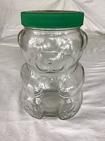 Front view glass teddy bear jar with green lid