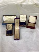 All five jewelry boxes open showing interiors and retailers’ stamps